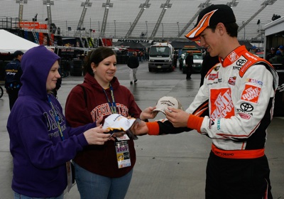 Joey Logano signs autographs for two fans while waiting out a rain delay at Martinsville Speedway. (Photo Credit: Geoff Burke/Getty Images)