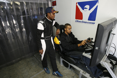 Dylan Smith of Randolph, Vt., watches Michael Cherry of Valrico, Fla., make laps on an iRacing simulator at Motor Mile Speedway. (Photo Credit: Tom Whitmore/Getty Images for NASCAR)
