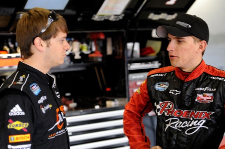 (Left to right) Landon Cassill and Plano, Texas native James Buescher talk in the NASCAR Nationwide Series garage during practice Friday at Texas Motor Speedway in Fort Worth, Texas. (Credit: John Harrelson/Getty Images for NASCAR)