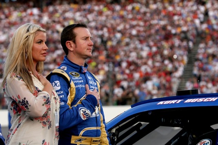 Kurt Busch stands with his wife Eva on the grid during the national anthem that was presented by The Commandant’s Own United States Marine Drum & Bugle Corps. (Credit: Chris Trotman/Getty Images)