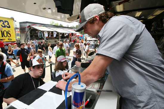 Travis Pastrana signs autographs for fans during practice for the NASCAR Sprint Cup Series Crown Royal Presents The Matthew and Daniel Hansen 400 at Richmond International Raceway on Apr. 29 in Richmond, Va. (Credit: Jerry Markland/Getty Images)