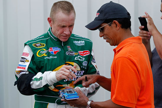 Mark Martin, driver of the No. 5 Quaker State/GoDaddy.com Chevrolet, signs his autograph for a fan in the garage during testing for the NASCAR Sprint Cup Series at Kentucky Speedway on July 7 in Sparta, Ky. (Credit: Geoff Burke/Getty Images for NASCAR)