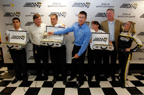 Flanked by Brinks security guards with three $1 million suitcases, (left to right) Robin Pemberton, NASCAR Vice President of Competition; Carl Edwards, driver of the No. 99 Aflac Ford Fusion; Tim Considine, director of sports marketing for Sprint; and Miss Sprint Cup Kim Coon announce the Sprint Summer Showdown presented by HTC EVO 3D on Sunday at New Hampshire Motor Speedway. (Credit: Geoff Burke/Getty Images for Sprint)