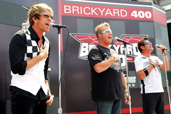 Joe Don Rooney (left), Gary LeVox (middle) and Jay DeMarcus (right) of Rascal Flatts perform prior to the NASCAR Sprint Cup Series Brickyard 400 at Indianapolis Motor Speedway on July 31 in Indianapolis, Ind. (Credit: Geoff Burke/Getty Images for NASCAR)