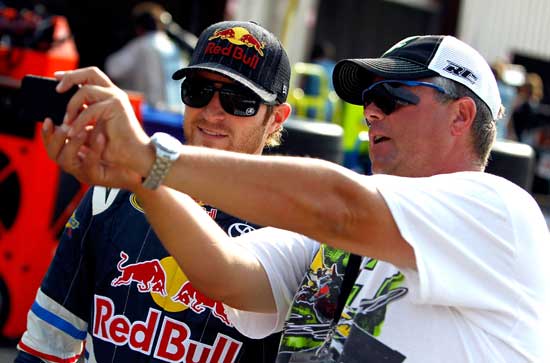 A fan takes a photo with Kasey Kahne (left), driver of the No. 4 Red Bull Toyota, during practice for the NASCAR Sprint Cup Series Pure Michigan 400 at Michigan International Speedway on Aug. 20 in Brooklyn, Mich. (Credit: Jeff Zelevansky/Getty Images for NASCAR)
