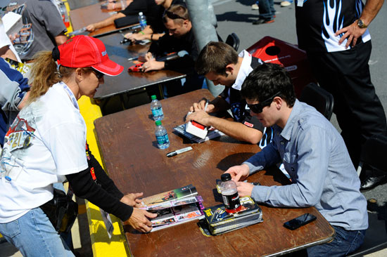 Ryan Truex (right) and Casey Roderick (left) sign autographs for a fan during the NASCAR Nationwide Series autograph session on Oct. 14 at the Charlotte Motor Speedway in Concord, N.C. (Credit: Jason Smith/Getty Images for NASCAR)