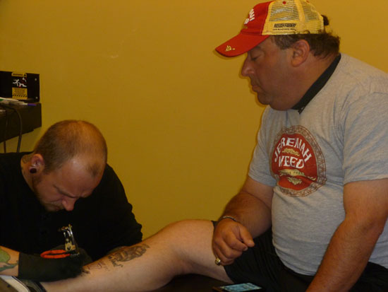 Matt Kenseth's spotter, Mike Calinoff, looks on as he gets his own tattoo courtesy of Jeremiah Weed 