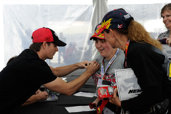 NASCAR Sprint Cup Series driver Jeff Gordon, No 24 Drive to End Hunger Chevrolet, signs autographs for a couple of fans at Charlotte Motor Speedway on Oct. 13 in Concord, N.C. (Credit: John Harrelson for Getty Images)