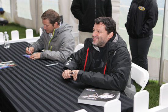 (Left to right) J.J. Yeley and Tony Stewart sign autographs for fans at Martinsville Speedway on Friday. (Credit: Tom Whitmore/Getty Images for NASCAR)