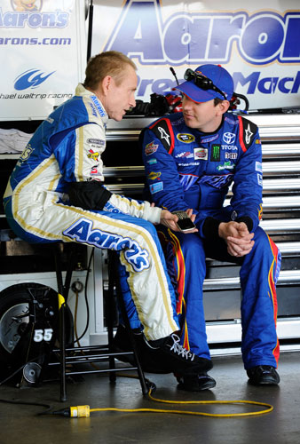 Mark Martin, driver of the No. 55 Aaron's Dream Machine Toyota, talks to Kyle Busch, driver of the No. 18 Snickers Toyota, in the garage area during practice for the NASCAR Sprint Cup Series Series Quicken Loans 400 at Michigan International Speedway on Friday in Brooklyn, Mich. (Credit: John Harrelson/Getty Images for NASCAR)
