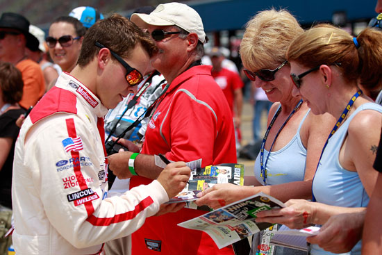 Trevor Bayne, driver of the No. 21 Motorcraft/Quick Lane Tire & Auto Center Ford, signs autographs during qualifying for the NASCAR Sprint Cup Series Quicken Loans 400 at Michigan International Speedway on Saturday in Brooklyn, Mich. (Credit: Geoff Burke/Getty Images for NASCAR)