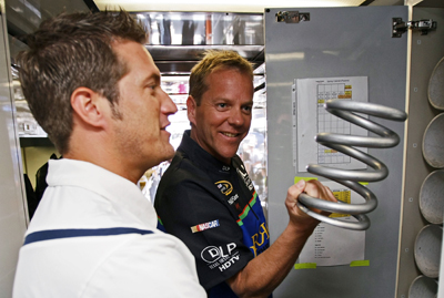 J.J. Yeley (L), driver of the #96 DLP HDTV Toyota, shows actor Kiefer Sutherland (R) a car spring and the inside of the hauler during the NASCAR Sprint Cup Series Sunoco Red Cross Pennsylvania 500 at the Pocono Raceway on August 3, 2008 in Long Pond, Pennsylvania. (Photo by Drew Hallowell/Getty Images for NASCAR)