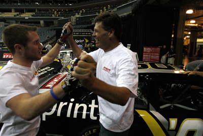 (Left to right) NASCAR Sprint Cup Series drivers Brian Vickers and Michael Waltrip celebrate winning the Media Pit Crew Challenge after pushing their car across the finish line Wednesday at Time Warner Cable Arena in Charlotte, N.C. (Photo Credit: Streeter Lecka/Getty Images for NASCAR)