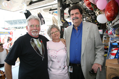 (Right to left) NASCAR President Mike Helton congratulates Brenda and Danny Barrett on their 15th anniversary on Saturday, where they were married, at Darlington Raceway. The Barretts drive the Official NASCAR Merchandise Trailer. (Photo Credit: Jerry Markland/Getty Images for NASCAR)