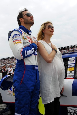 Jimmie Johnson and wife Chandra – who are on baby watch as the due date of their daughter approaches – stand on pit road during the singing of the national anthem at Pocono Raceway. Johnson said on Friday that Aric Almirola would be available to drive the No. 48 car if Chandra goes into labor during an upcoming race weekend. (Credit: Chris Trotman/Getty Images for NASCAR)