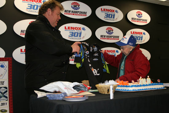 Jerry Gappens, president of New Hampshire International Speedway, presents 100-year-old Rachel Gilbert with an autographed shirt from her favorite driver Carl Edwards. (Credit: Jonathan Stallsmith)