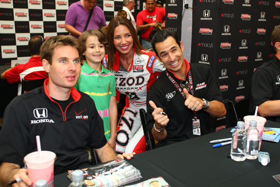 Will Power and Helio Castroneves pose for photos with a young fan at a autograph signing event