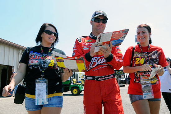 Kevin Harvick signs autographs for fans as he walks through the garage with them on Friday at Michigan International Speedway. (Credit: Jared C. Tilton/Getty Images for NASCAR)