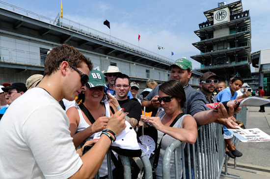 Trevor Bayne (left), driver of the No. 21 Motorcraft/Quick Lane Tire & Auto Center Ford, signs autographs for fans before practice for the NASCAR Sprint Cup Series Brickyard 400 at Indianapolis Motor Speedway on July 29 in Indianapolis, Ind. (Credit: John Harrelson/Getty Images for NASCAR)