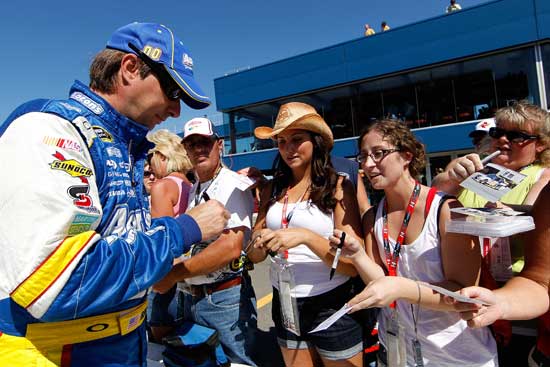 David Reutimann, driver of the No. 00 Aaron's Dream Machine Toyota, signs autographs on pit road after qualifying for the NASCAR Sprint Cup Series Pure Michigan 400 at Michigan International Speedway on Aug. 19 in Brooklyn, Mich. (Credit: Wesley Hitt/Getty Images for NASCAR)