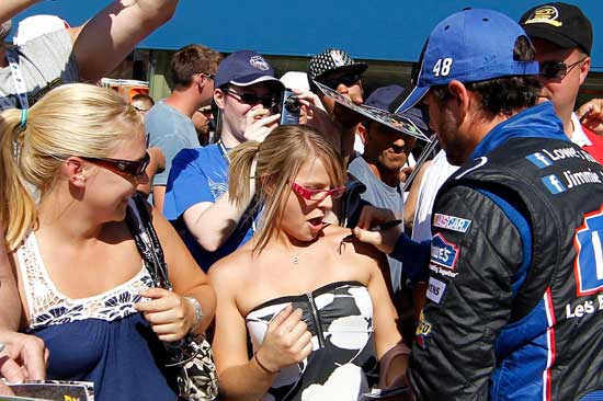 Jimmie Johnson (right), driver of the No. 48 Lowe's Chevrolet, signs a fan's shoulder on pit road after qualifying for the NASCAR Sprint Cup Series Pure Michigan 400 at Michigan International Speedway on Aug. 19 in Brooklyn, Mich. (Credit: Wesley Hitt/Getty Images for NASCAR)