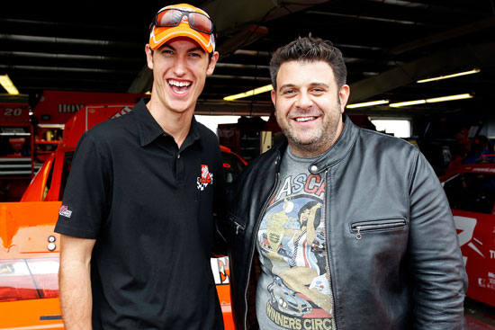 Joey Logano (left), driver of the No. 20 The Home Depot Toyota, and Adam Richman (right), host of Man v. Food pose in the garage area prior to the NASCAR Sprint Cup Series Heluva Good! Sour Cream Dips at the Glen at Watkins Glen International on Aug. 14 in Watkins Glen, N.Y. (Credit: Geoff Burke/Getty Images for NASCAR)