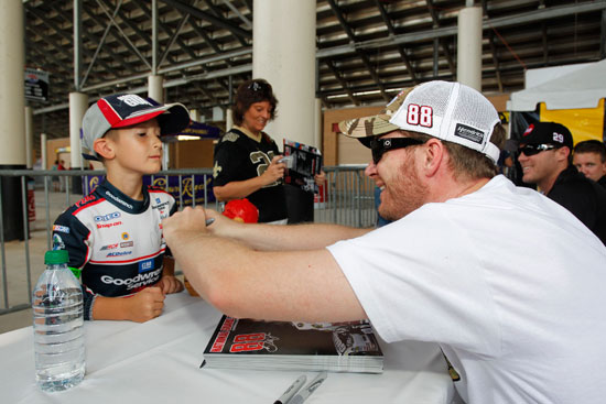 NASCAR Sprint Cup Series driver Dale Earnhardt Jr. signs an autograph for a young fan at Atlanta Motor Speedway on Sept. 2 in Hampton, Ga. (Credit: By Geoff Burke/Getty Images for NASCAR)