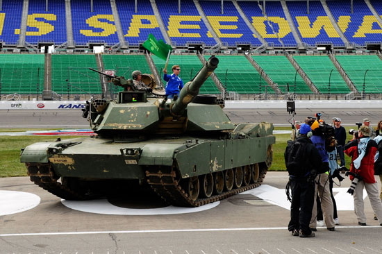 Brad Keselowski, driver of the No. 2 Miller Lite Dodge, stands on a tank as he waves a flag to signal the a bulldozer to start diggin up pit road as part of a repaving project on the track immediately following during the NASCAR Sprint Cup Series STP 400 on Sunday at Kansas Speedway in Kansas City, Kan. (Credit: John Harrelson/Getty Images for NASCAR)