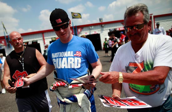A freshly-shaved Dale Earnhardt Jr. signs autographs in the Talladega Superspeedway garage. (Credit: Tom Pennington/Getty Images for NASCAR)
