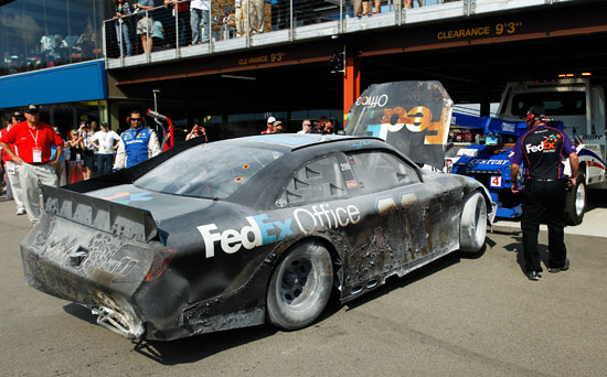The No. 11 FedEx Office Toyota of Denny Hamlin is towed into the garage area after an incident during the NASCAR Sprint Cup Series Quicken Loans 400 at Michigan International Speedway on Sunday in Brooklyn, Mich. (Credit: Wesley Hitt/Getty Images for NASCAR)